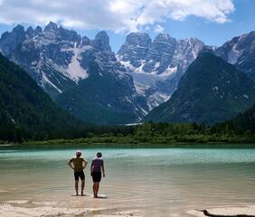 Due mountain biker stanno con i piedi nell’acqua del Lago di Braies
