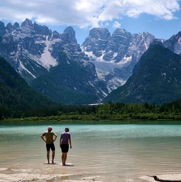 Due mountain biker stanno con i piedi nell’acqua del Lago di Braies