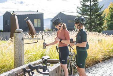 Due donne in abbigliamento da ciclismo riempiono le loro borracce a una fontana