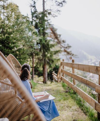 A woman is sitting in a lounge in the garden