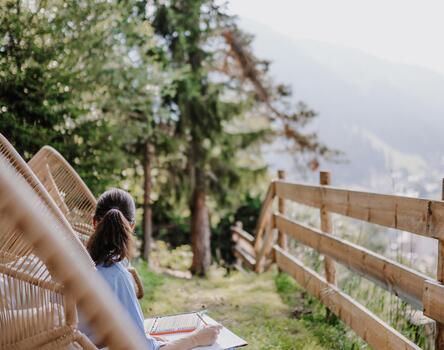 A woman is sitting in a lounge in the garden