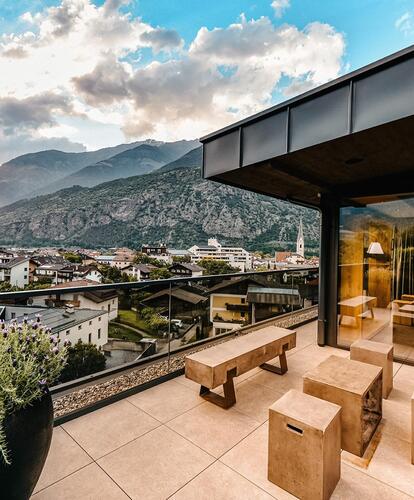 Part of the sauna area viewed from the terrace; in the background, the village and the mountain scenery behind it are visible.