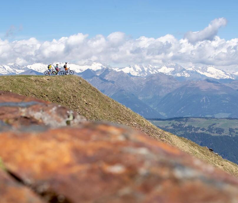 Three people with their bicycles on a mountain summit