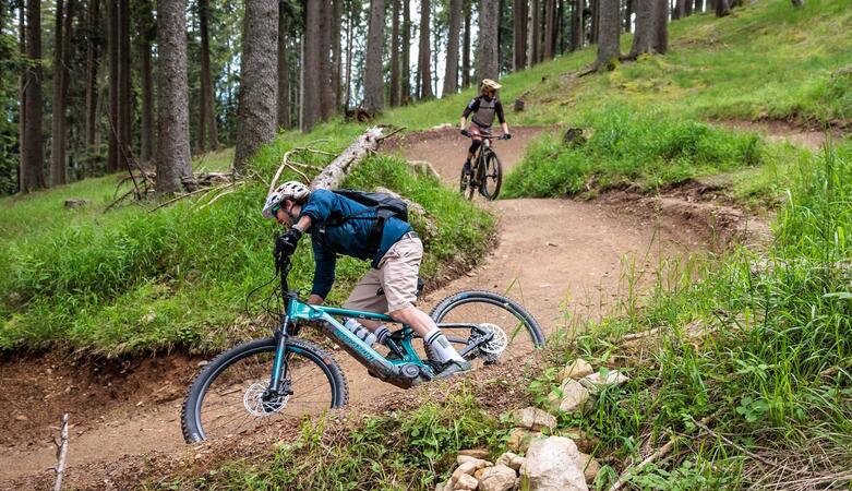 Two people are riding down a trail