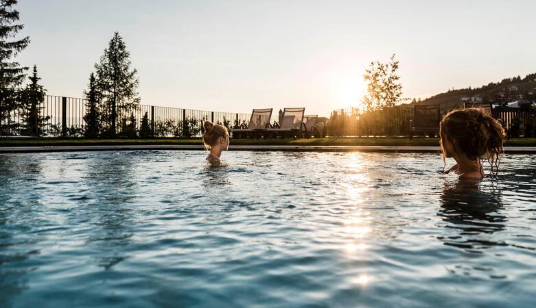 Two women relax in the outdoor pool at Hotel Erica