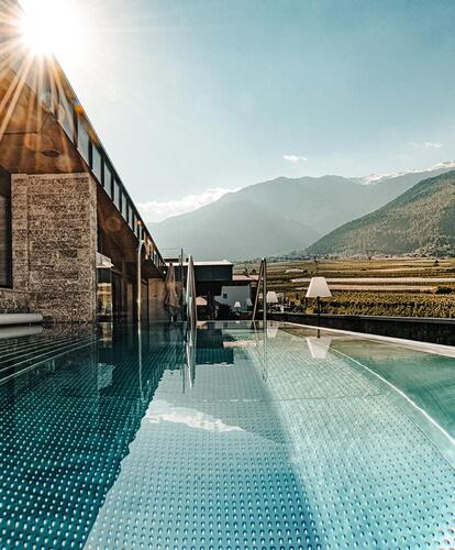 Exterior view of the pool with a view of the surrounding sunlit valley and mountains in the background.