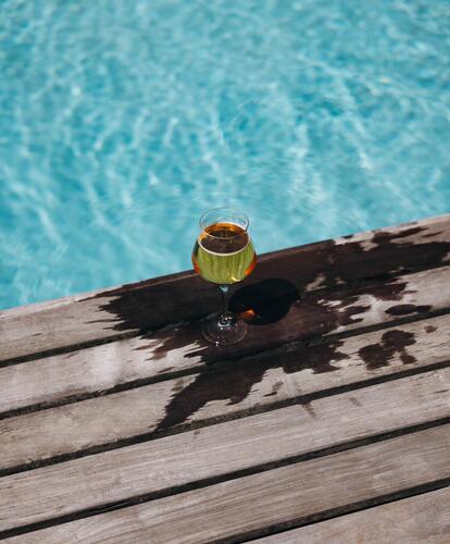 A cocktail sits at the edge of the outdoor pool