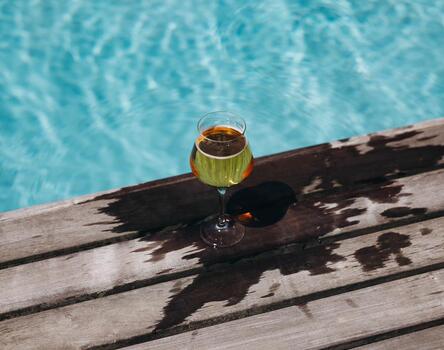 A cocktail sits at the edge of the outdoor pool