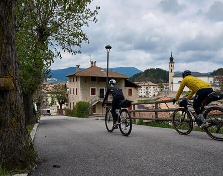 Two cyclists are riding through a village