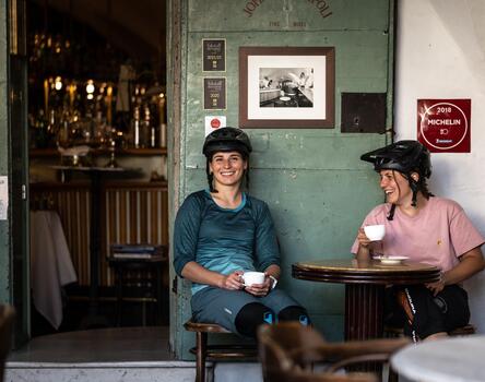 Zwei Frauen mit Fahrradhelm trinken einen Kaffee