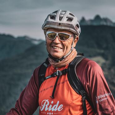 Nahaufnahme des Gastgebers Toni in roter Fahrradkleidung und Helm.