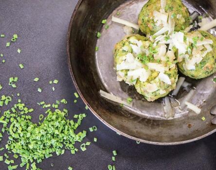 Canederli agli spinaci serviti con formaggio ed erba cipollina