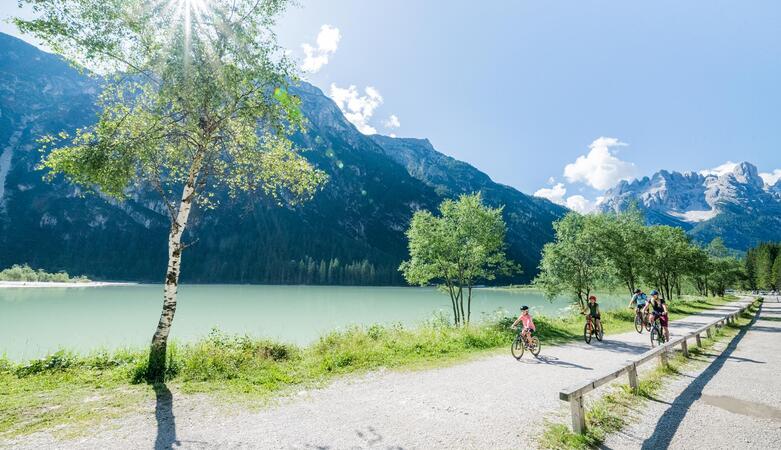 Una famiglia passa in bicicletta davanti al Lago di Landro