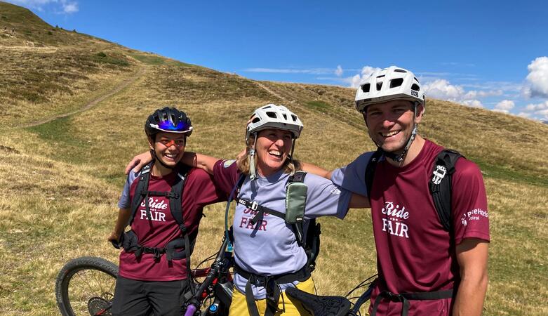 Drei Radfahrer mit ihren Fahrrädern vor einer Almlandschaft