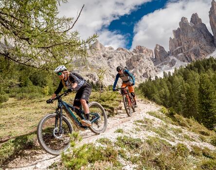 A man and a woman ride a trail on their mountain bikes