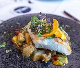 Primo piano di un piatto con verdure e un filetto di pesce sopra.
