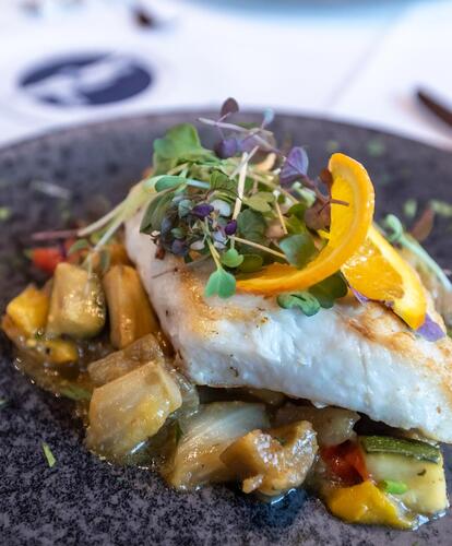 Primo piano di un piatto con verdure e un filetto di pesce sopra.