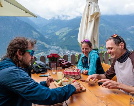 Drei Personen genießen eine Brotzeit auf einer Hütte