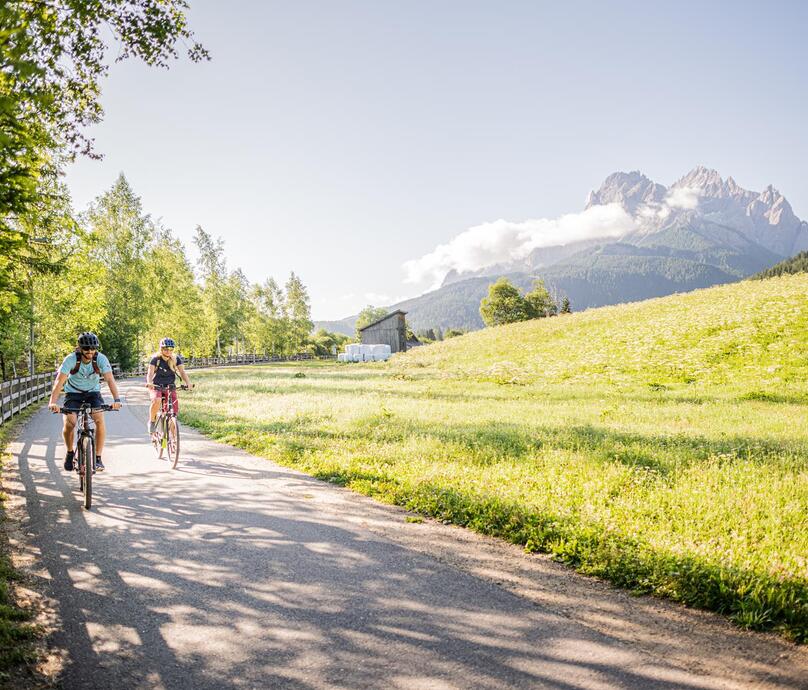 Two cyclists ride on a bike path