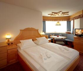 Hotel room at Hotel Piccolo with a double bed, wooden furniture and a sitting area by the window.