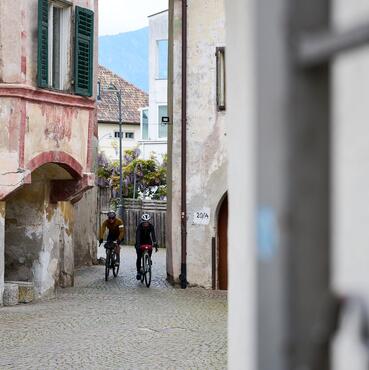 Due ciclisti attraversano un vicolo stretto