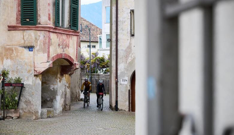Due ciclisti attraversano un vicolo stretto