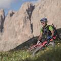 Der Gastgeber Gunther Linder sitzt neben seinem Fahrrad auf einer Wiese; sind die massiven Dolomiten zu sehen.