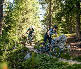 Zwei Frauen fahren mit ihren Mountainbikes einen Trail