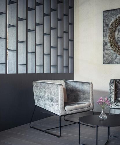 Modern seating area in the hotel with two large armchairs, small tables, and a large picture on the wall.