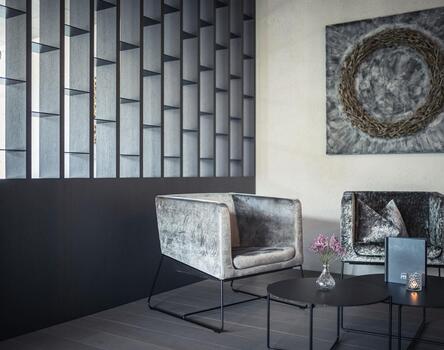 Modern seating area in the hotel with two large armchairs, small tables, and a large picture on the wall.