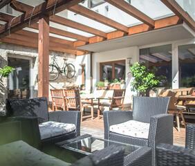Una terrazza coperta con poltrone confortevoli, tavoli e sedie.