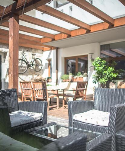 Una terrazza coperta con poltrone confortevoli, tavoli e sedie.