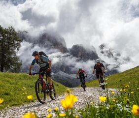 Tre mountain biker pedalano in salita su un trail