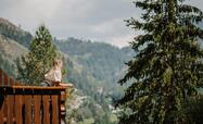 Frau auf Balkon vor Wald und Bergen