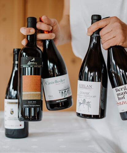 A man is holding several bottles of wine in his hands
