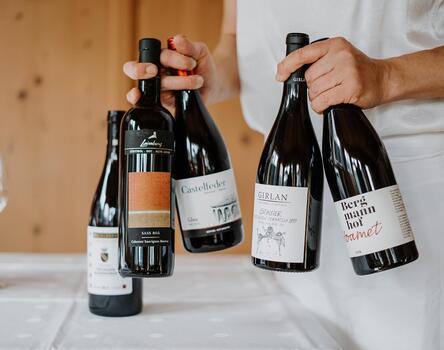 A man is holding several bottles of wine in his hands