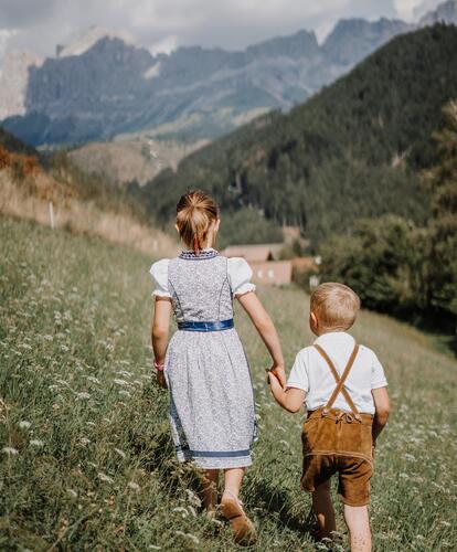 Two children are walking across a meadow