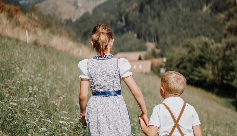 Two children are walking across a meadow