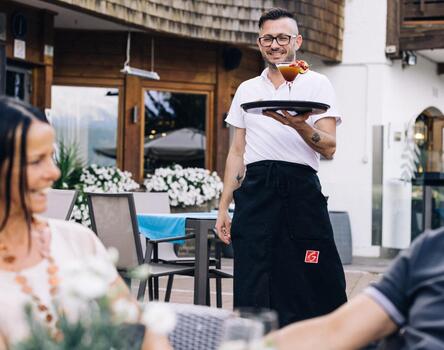 Un cameriere porta da mangiare a un gruppo di ospiti su una terrazza di un ristorante