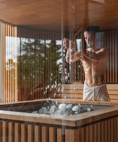 A sauna master prepares an infusion in the sauna
