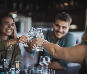 Close-up of three people clinking glasses together.
